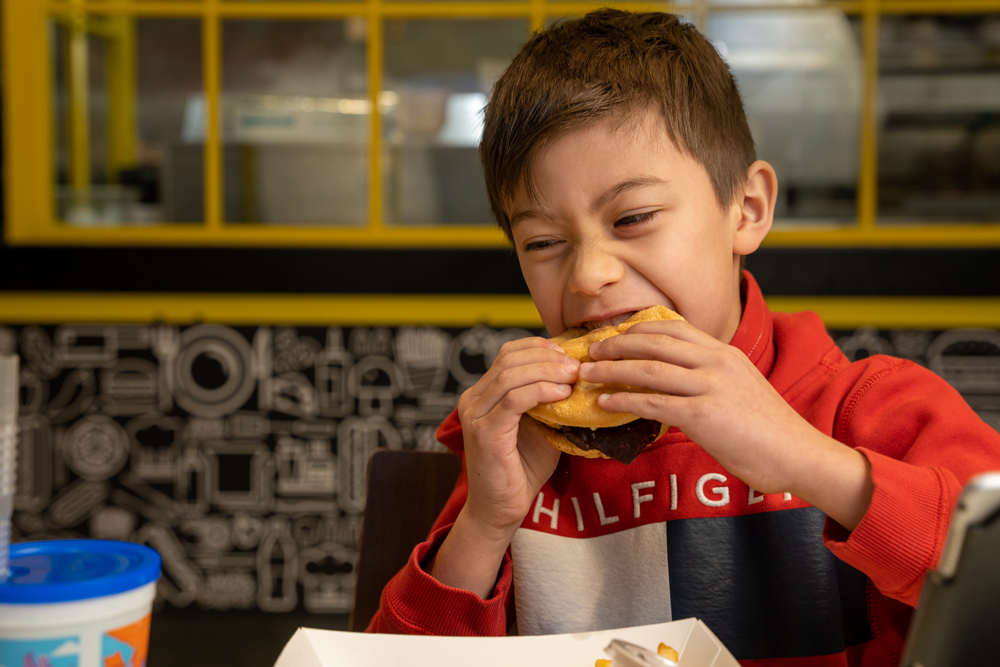 Young kid eating a burger at Hynsons burger in oklahoma city
